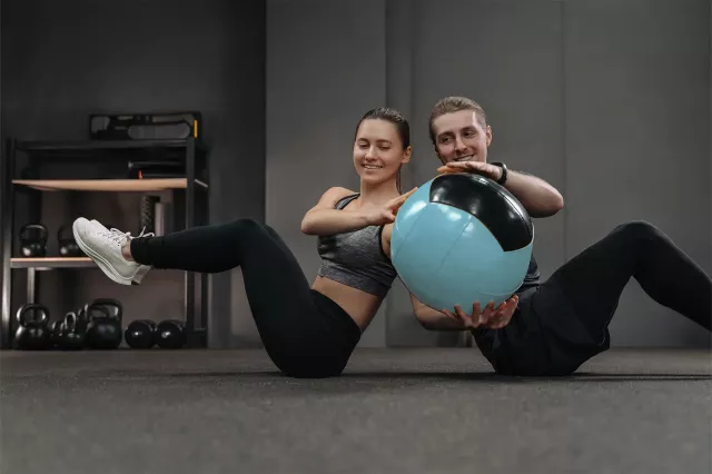 Zwei Personen trainieren mit Gymnastikball